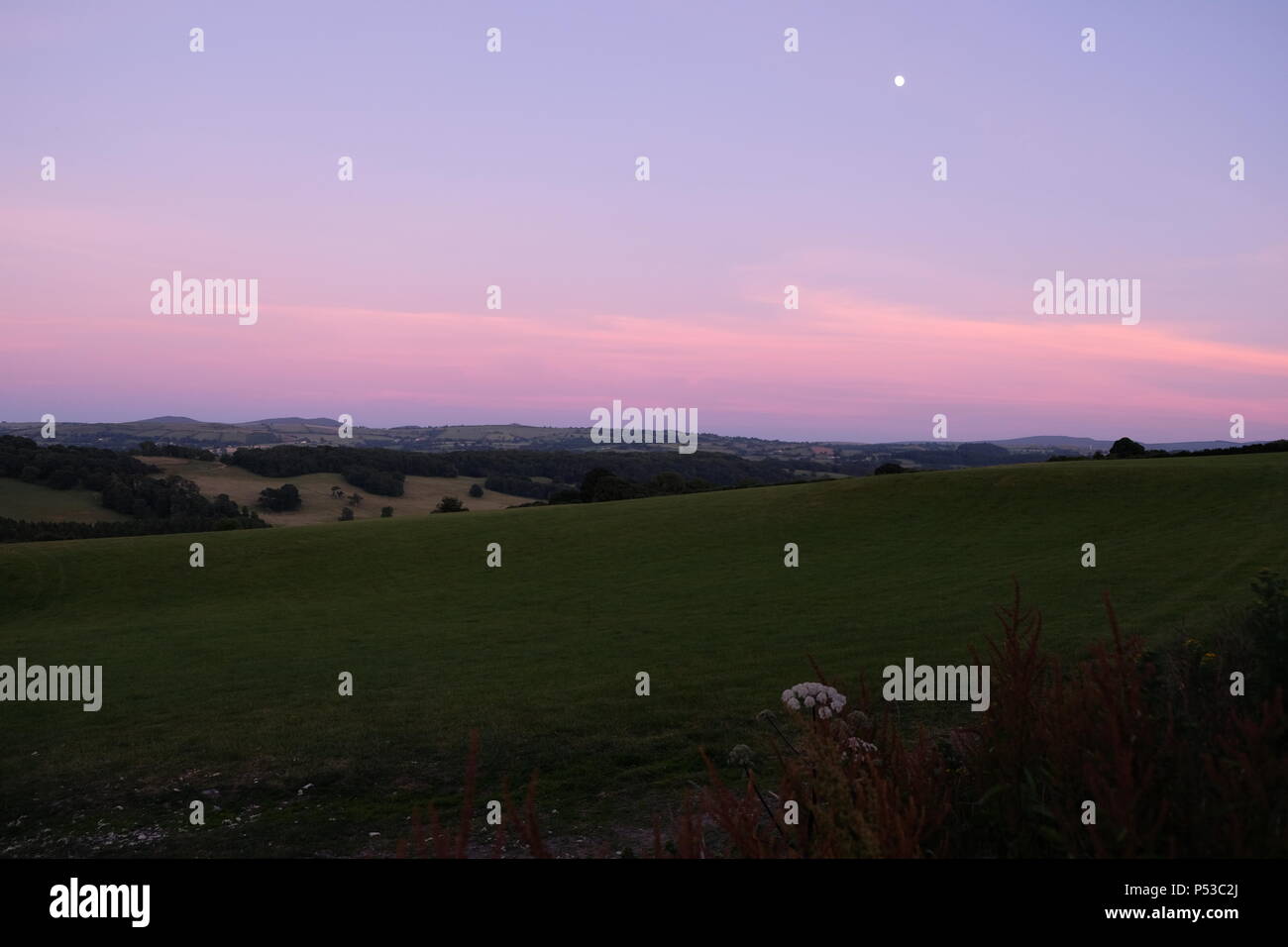 Luna sul cielo rosa sopra le colline Welsh Foto Stock