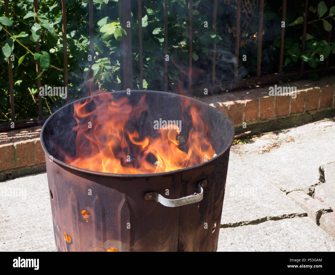 La distruzione di rifiuti per mezzo di combustione in un inceneritore giardino bin. Cause di fumo, che l'inquinamento atmosferico. Non aiuta l'ambiente. Foto Stock