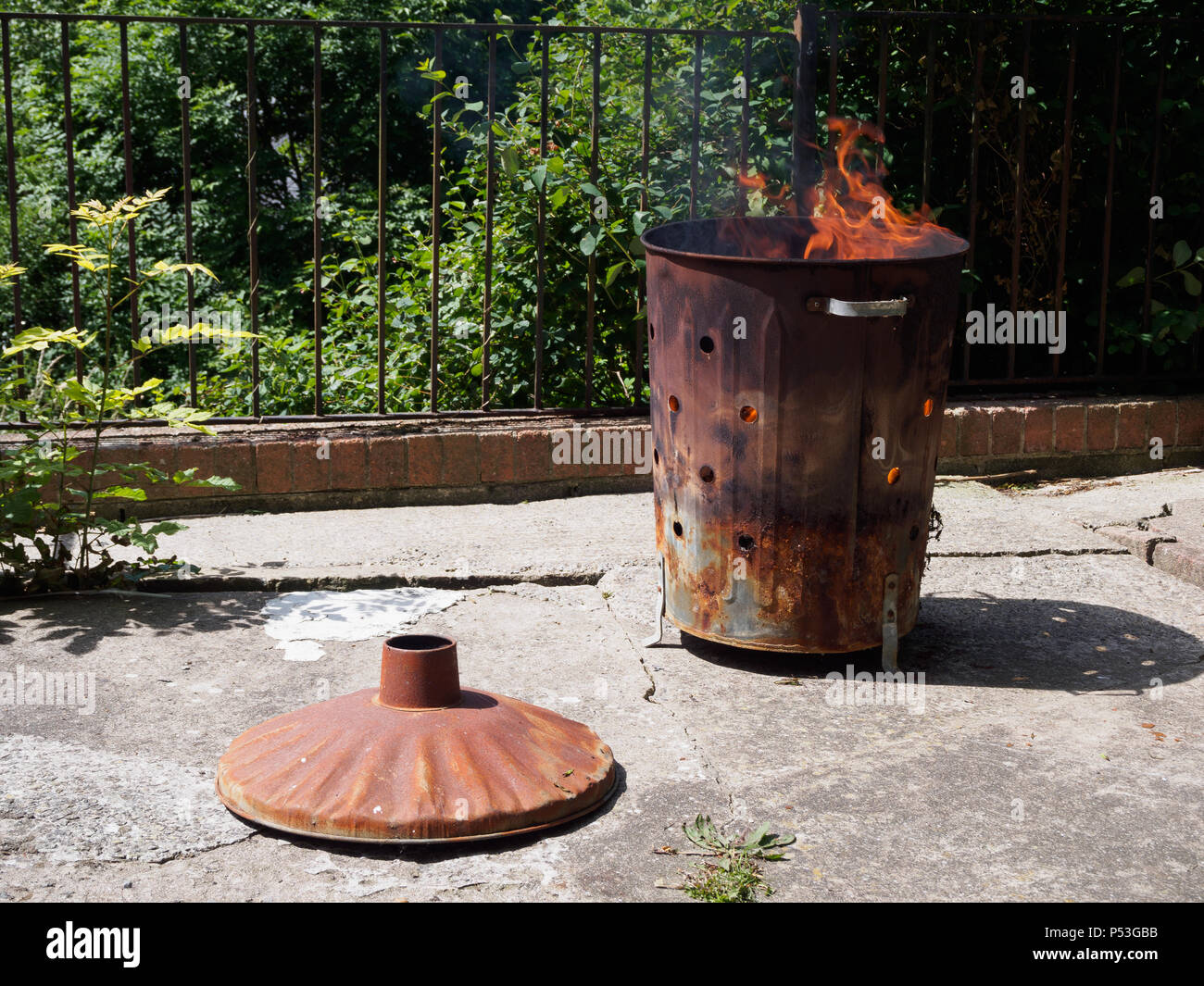 La distruzione di rifiuti per mezzo di combustione in un inceneritore giardino bin. Cause di fumo, che l'inquinamento atmosferico. Non aiuta l'ambiente. Foto Stock