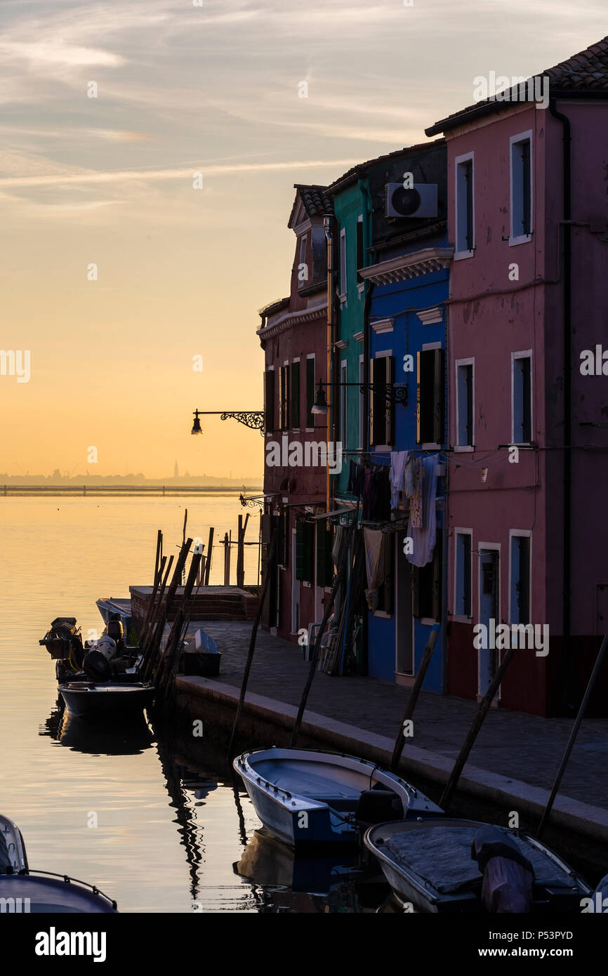 Waterfront canal sull isola di Burano, case e barche parcheggiato sullo sfondo dello splendido tramonto. Italia Foto Stock