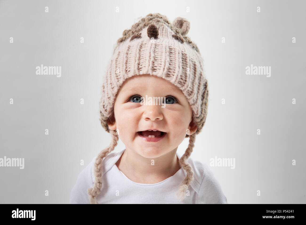 Ritratto di una bellissima bambina in un enorme berretto lavorato a maglia. Isolato su sfondo bianco. Foto Stock