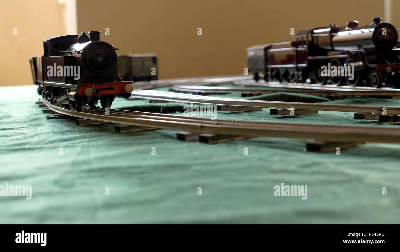 Primo piano vintage modello treno elettrico formato da una locomotiva a vapore e un verde le autovetture in esecuzione su rotaie Foto Stock