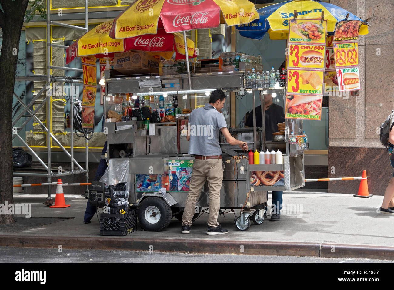 Un cibo non identificato venditore preparare un hot dog per un cliente in Midtown Manhattan sulla Fifth Avenue. Foto Stock