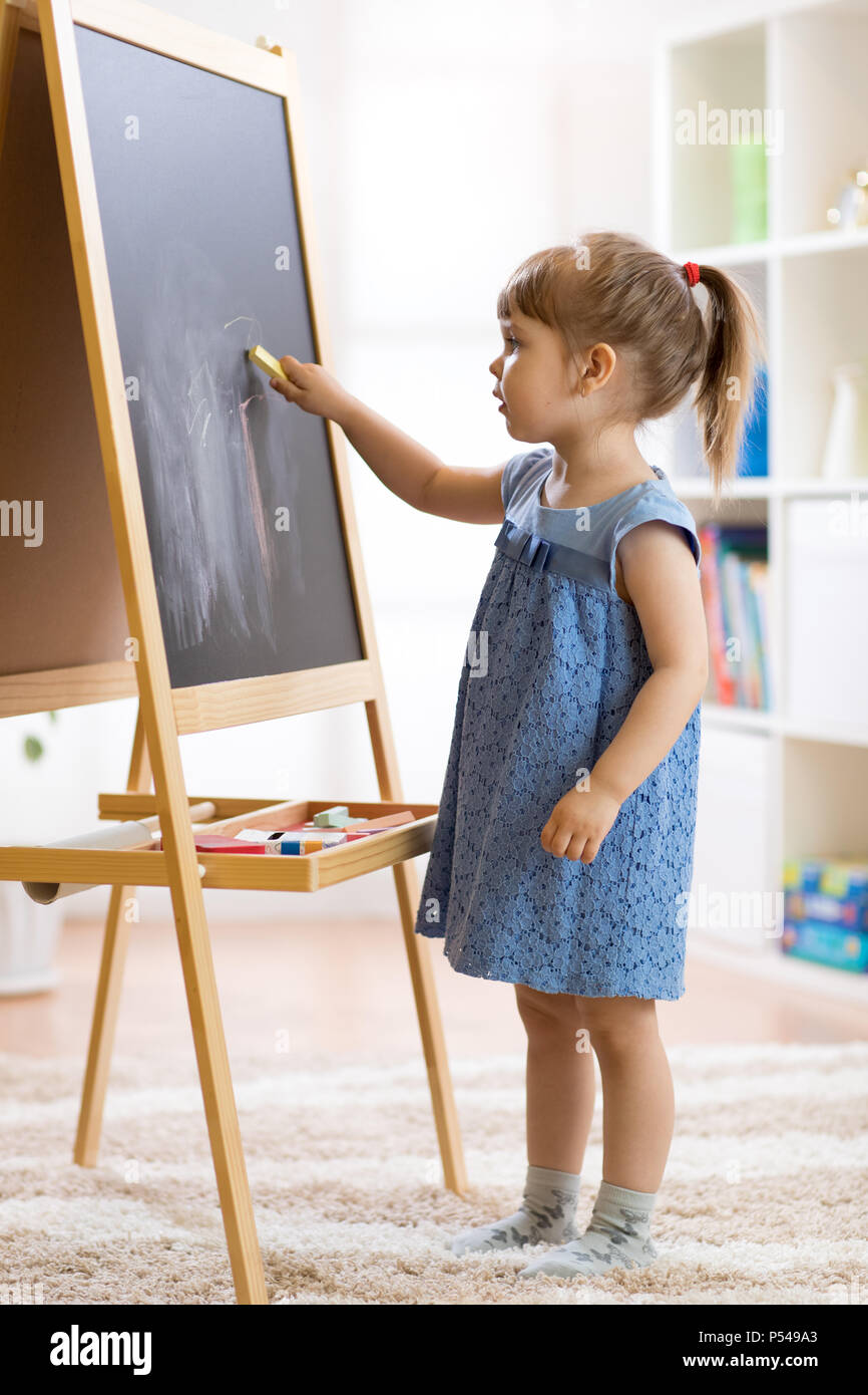 Bambina disegna con il gesso sulla lavagna Foto Stock