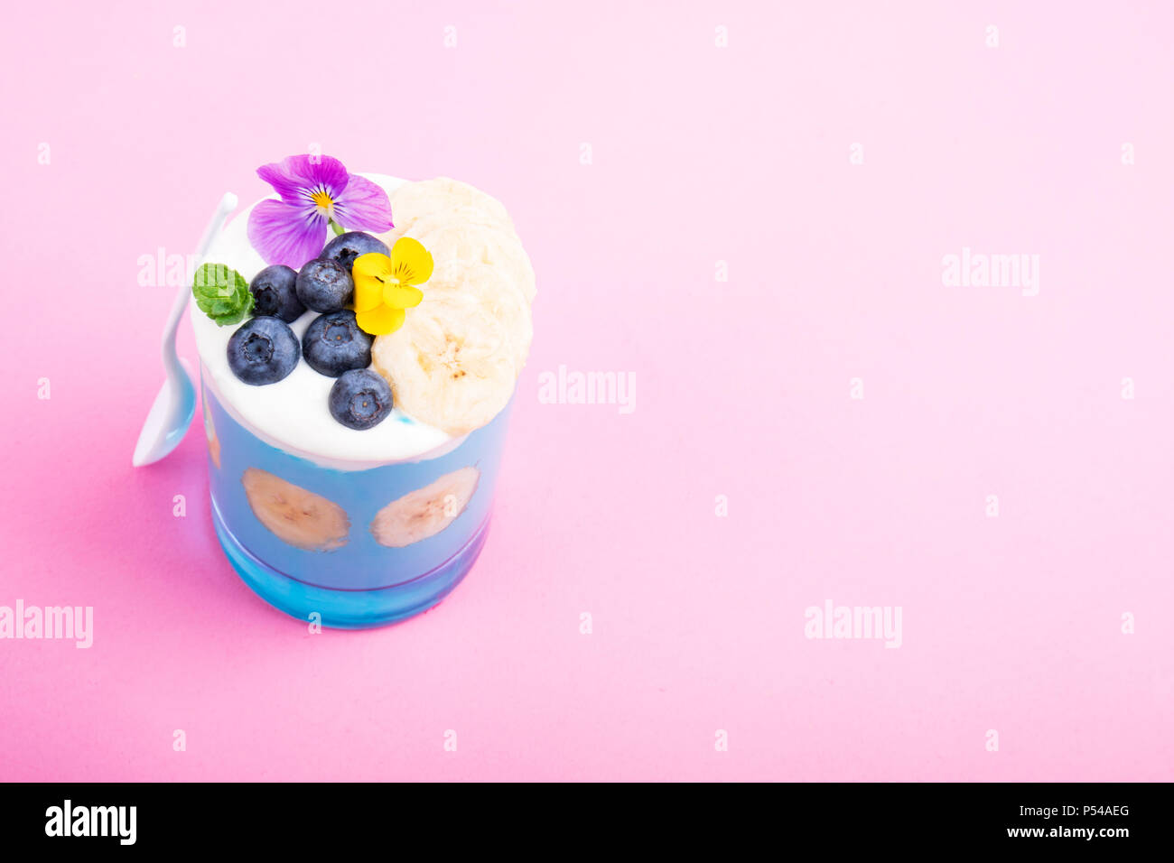 I frullati dessert con frutta, bacche, dadi e fiori su sfondo rosa. Tropical frullato sano. Una sana prima colazione, alimentazione vegetariana, lunch conce Foto Stock