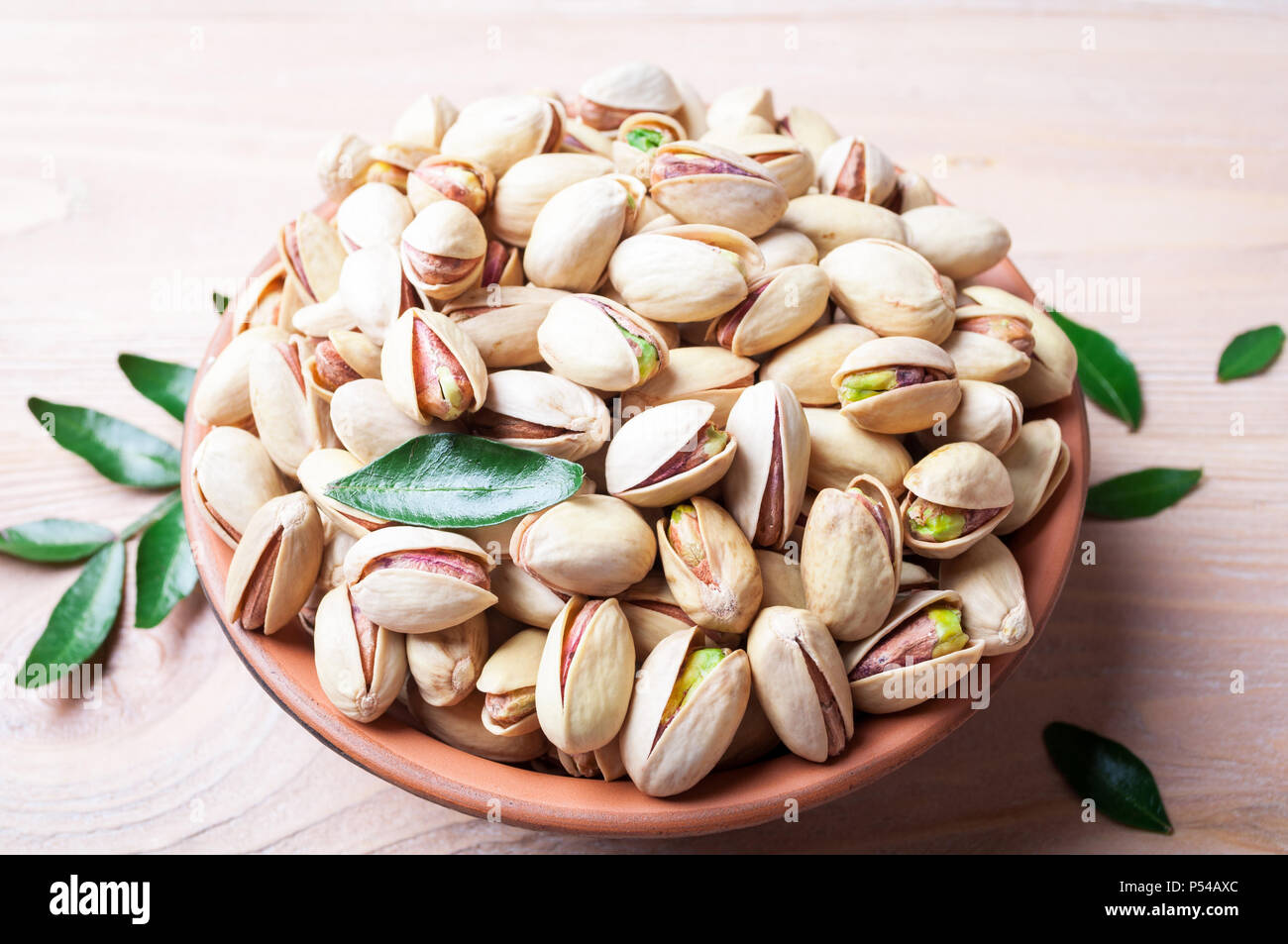 Pistacchi Noci in ciotola. Il pistacchio con foglie. Cibo sano, spuntini e cibo vegetariano Foto Stock