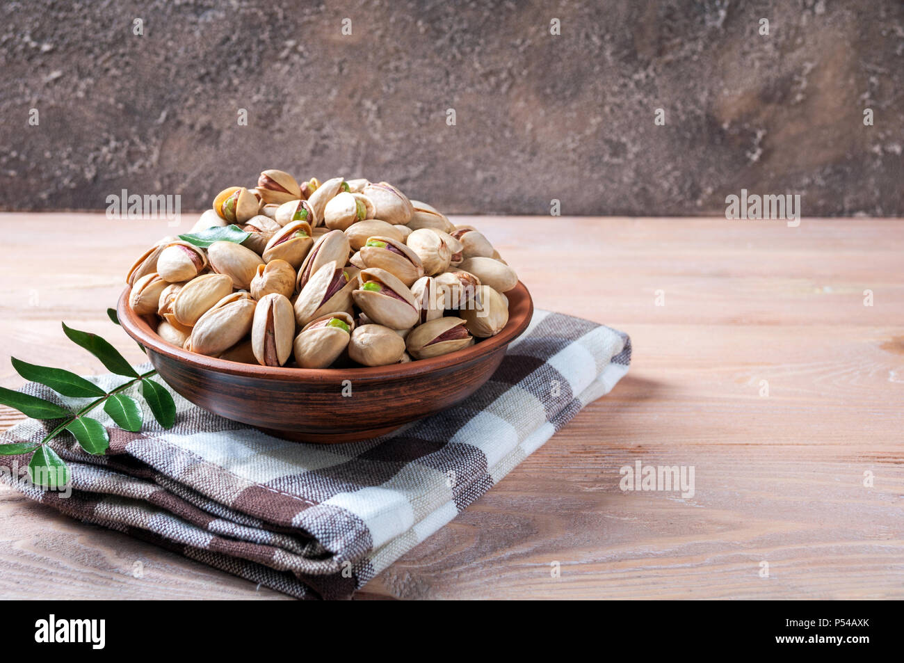 Pistacchi Noci in ciotola. Il pistacchio con foglie. Cibo sano, spuntini e cibo vegetariano. Spazio di copia Foto Stock