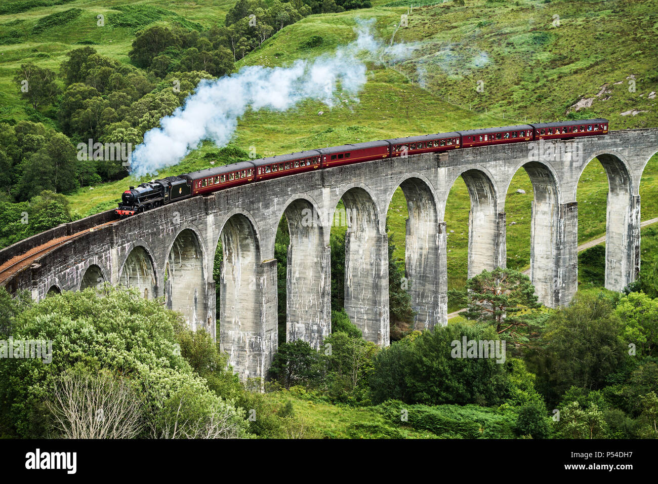 Il Giacobita treno a vapore che attraversa il Glenfinnan viadotto ferroviario, Scozia Foto Stock