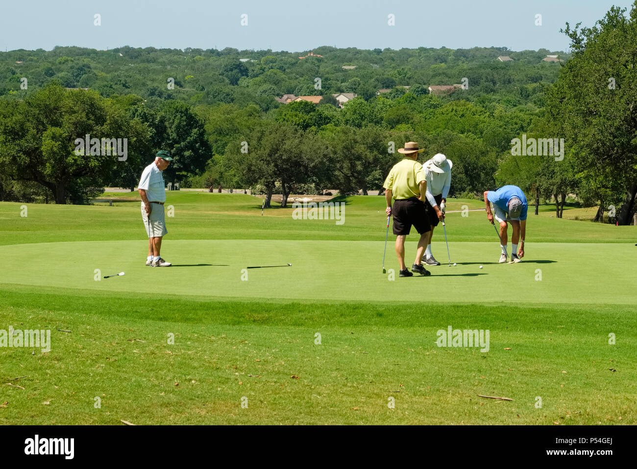 4 uomini anziani che si godono una partita di golf su un campo da golf della comunità di pensione per adulti di Sun City Texas Foto Stock