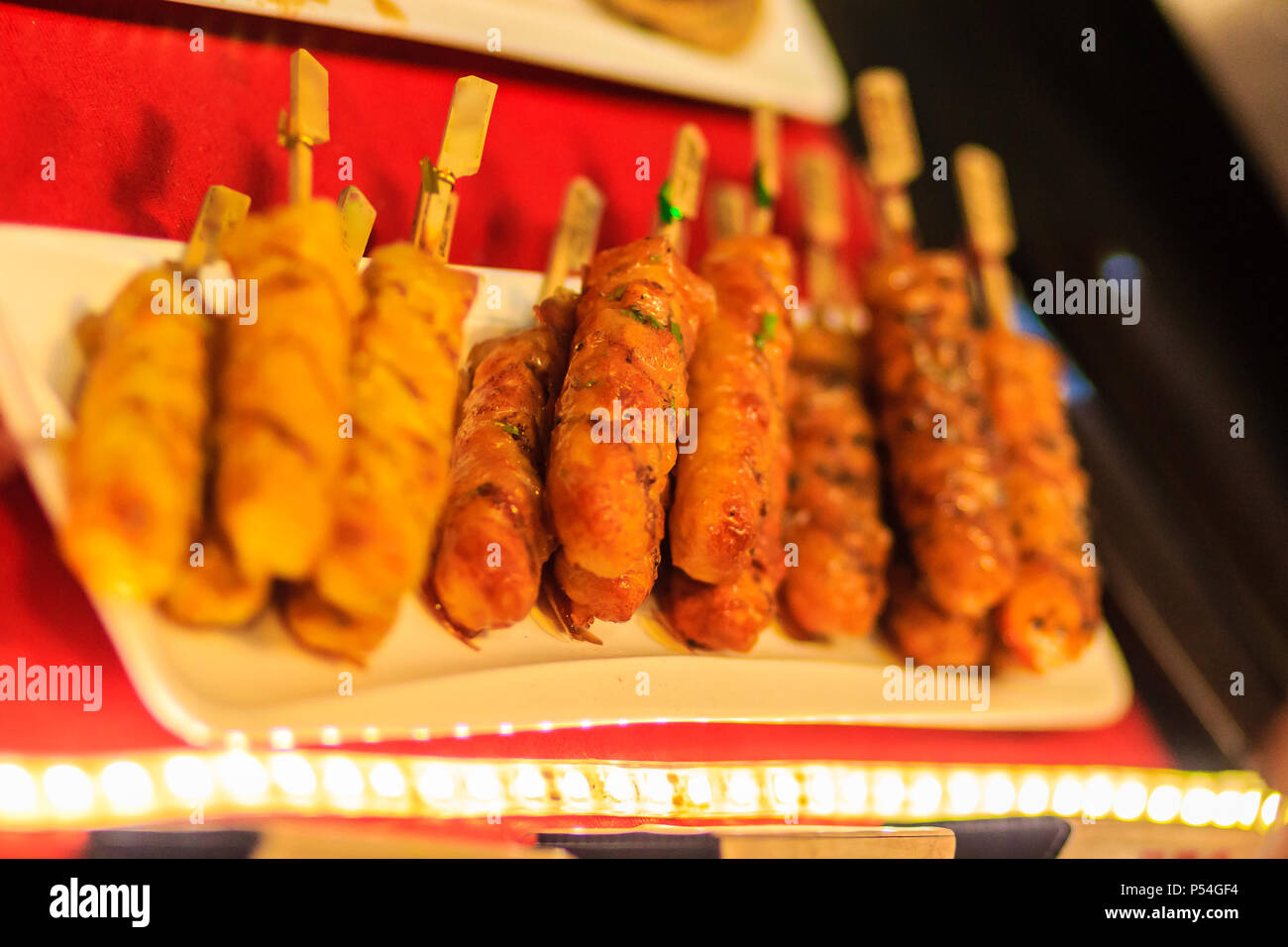 Chiudere il fornitore grigliare carne di maiale satay, Tailandese bistecca di carne di maiale arrosto grigliare sul fuoco schermo al mercato notturno di Bangkok, Tailandia. Foto Stock