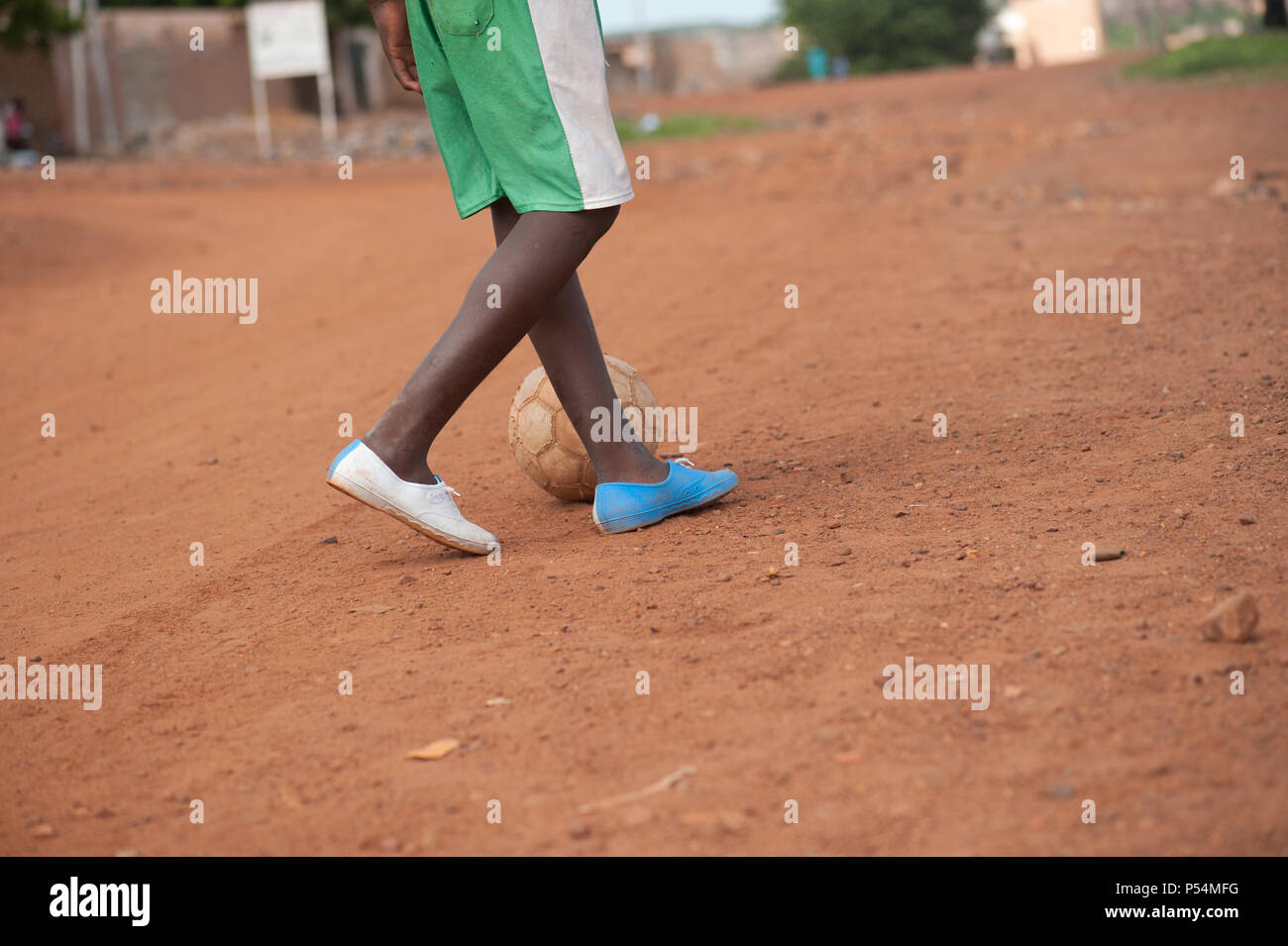Mali, Africa - circa agosto 2009 - nero piccolo ragazzo giocando a calcio vicino a Bamako nella sabbia rossa Foto Stock