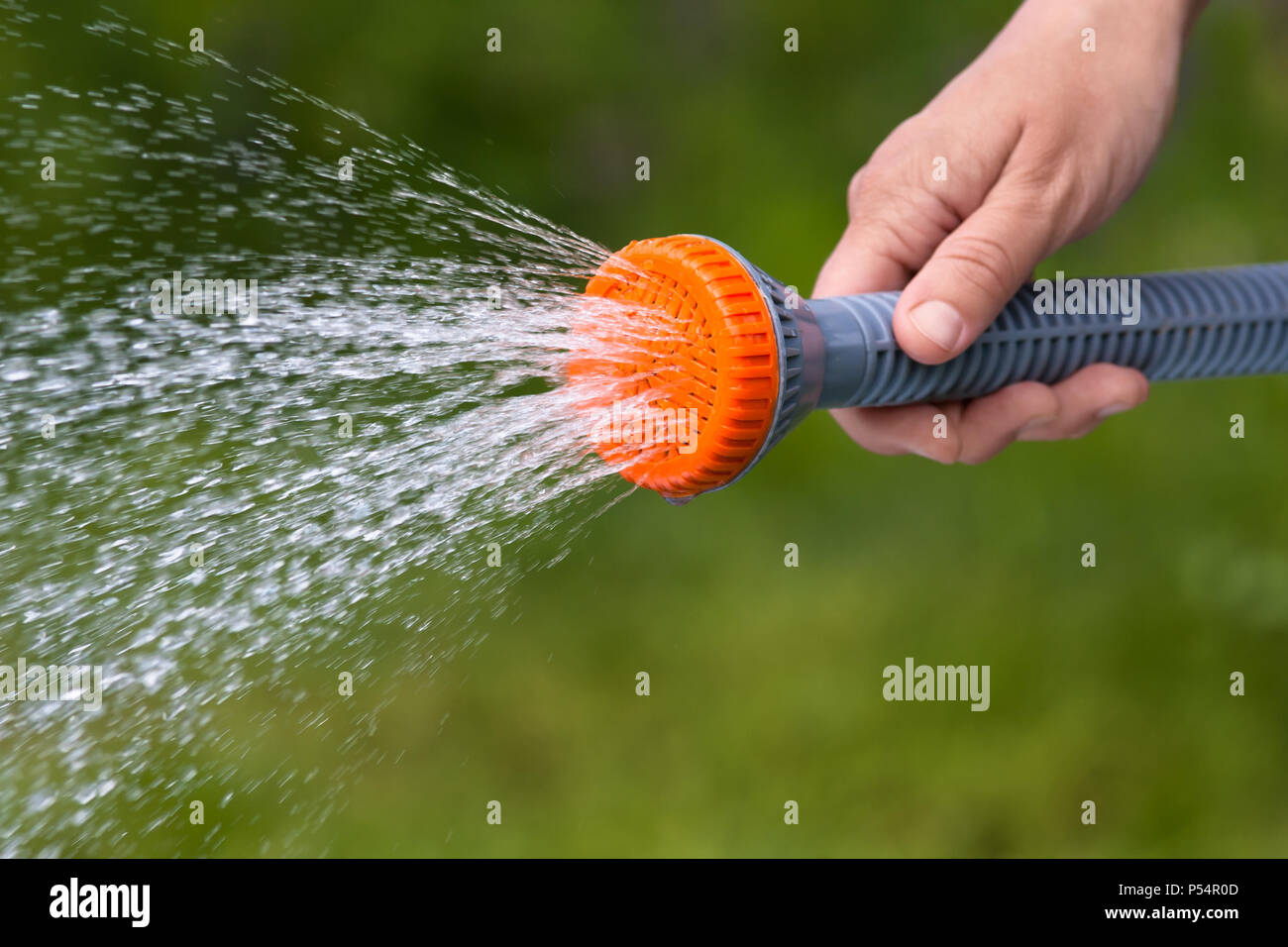 Lato giardino di irrigazione con sprinkler su sfondo sfocato, primo piano Foto Stock
