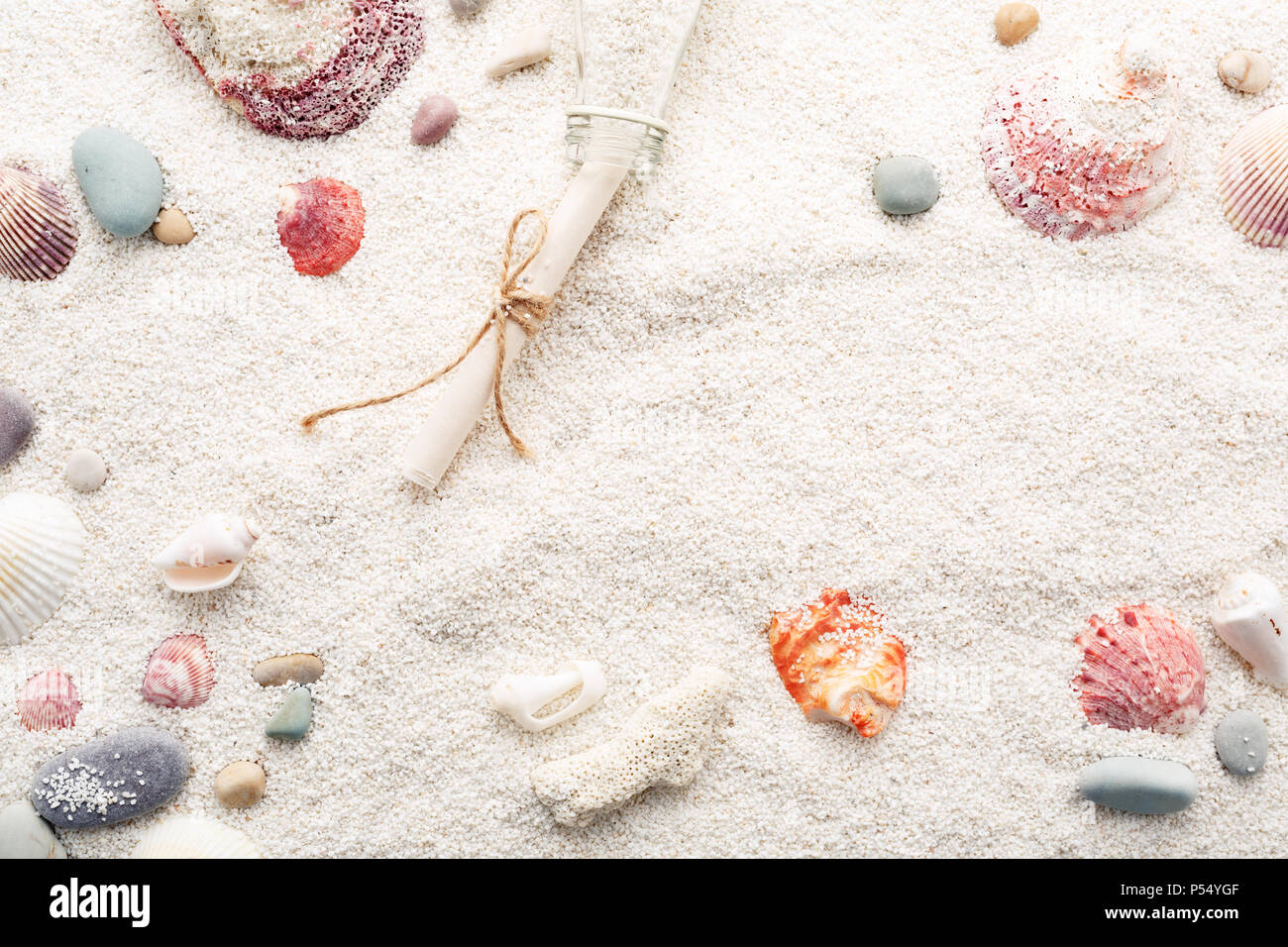 Colorate conchiglie e ciottoli di mare sulla spiaggia bianca di sabbia e una bottiglia con un messaggio. La vacanza estiva concetto. Copia di sfondo spazio. Foto Stock