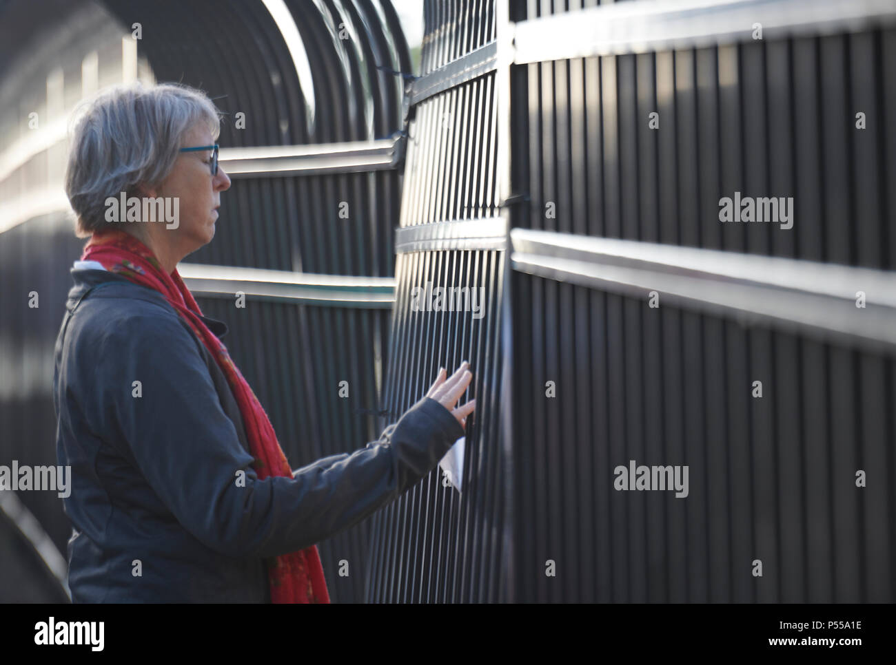 Seatac, Washington, Stati Uniti d'America. 24 Giugno, 2018. Il Rev. Maria Kohlstaedt Huycke prega presso la recinzione che circonda la Federal centro di detenzione a Seatac, Washington, inizio giugno 24 durante una veglia di preghiera a sostegno di genitori immigrati all interno del carcere che sono stati separati dai loro figli. Huycke è un pastore del Regno chiesa metodista. Credito: Paul Jeffrey/Alamy Live News Foto Stock