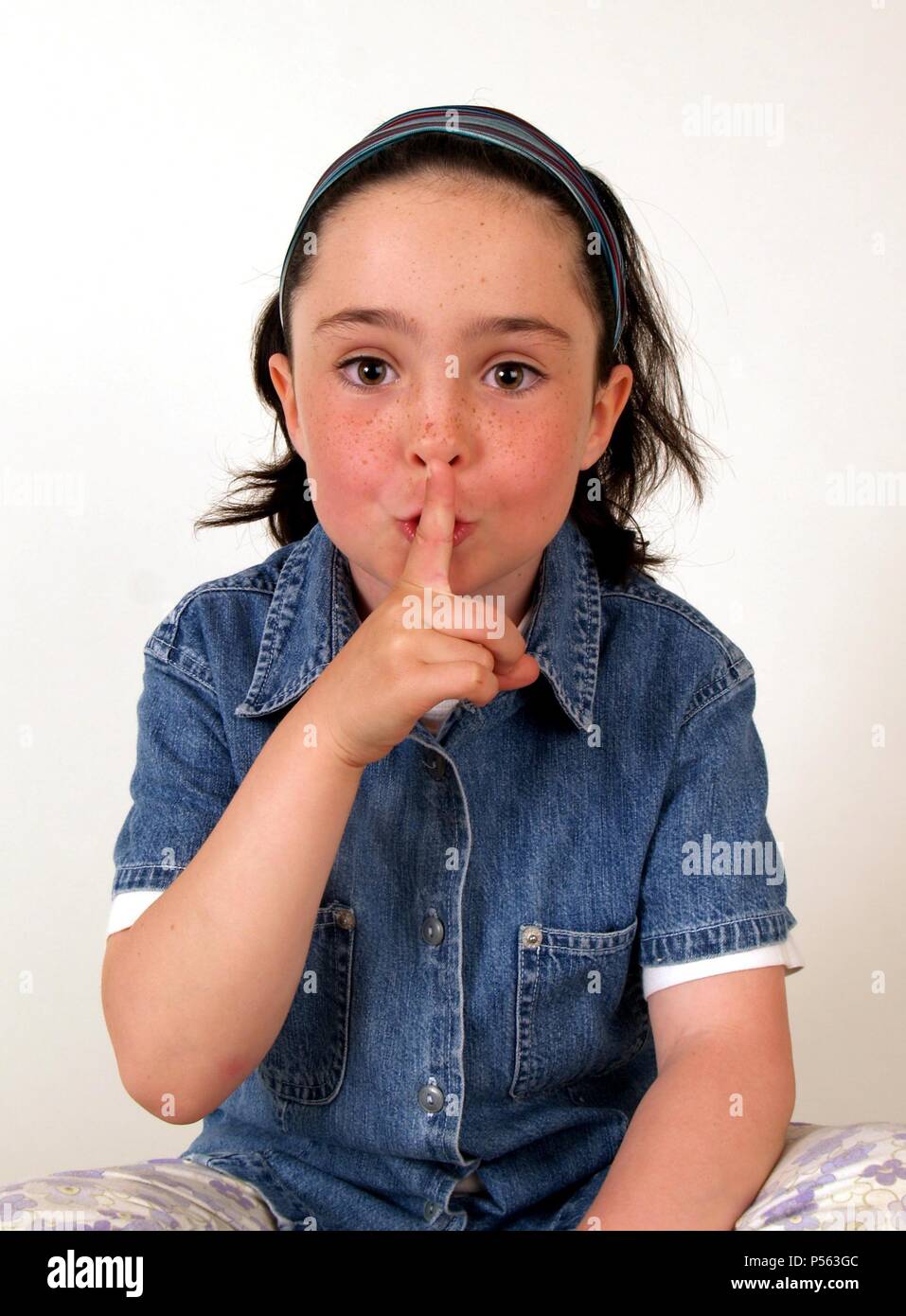 NIÑA PIDIENDO SILENCIO con el dedo en los labios. Foto Stock