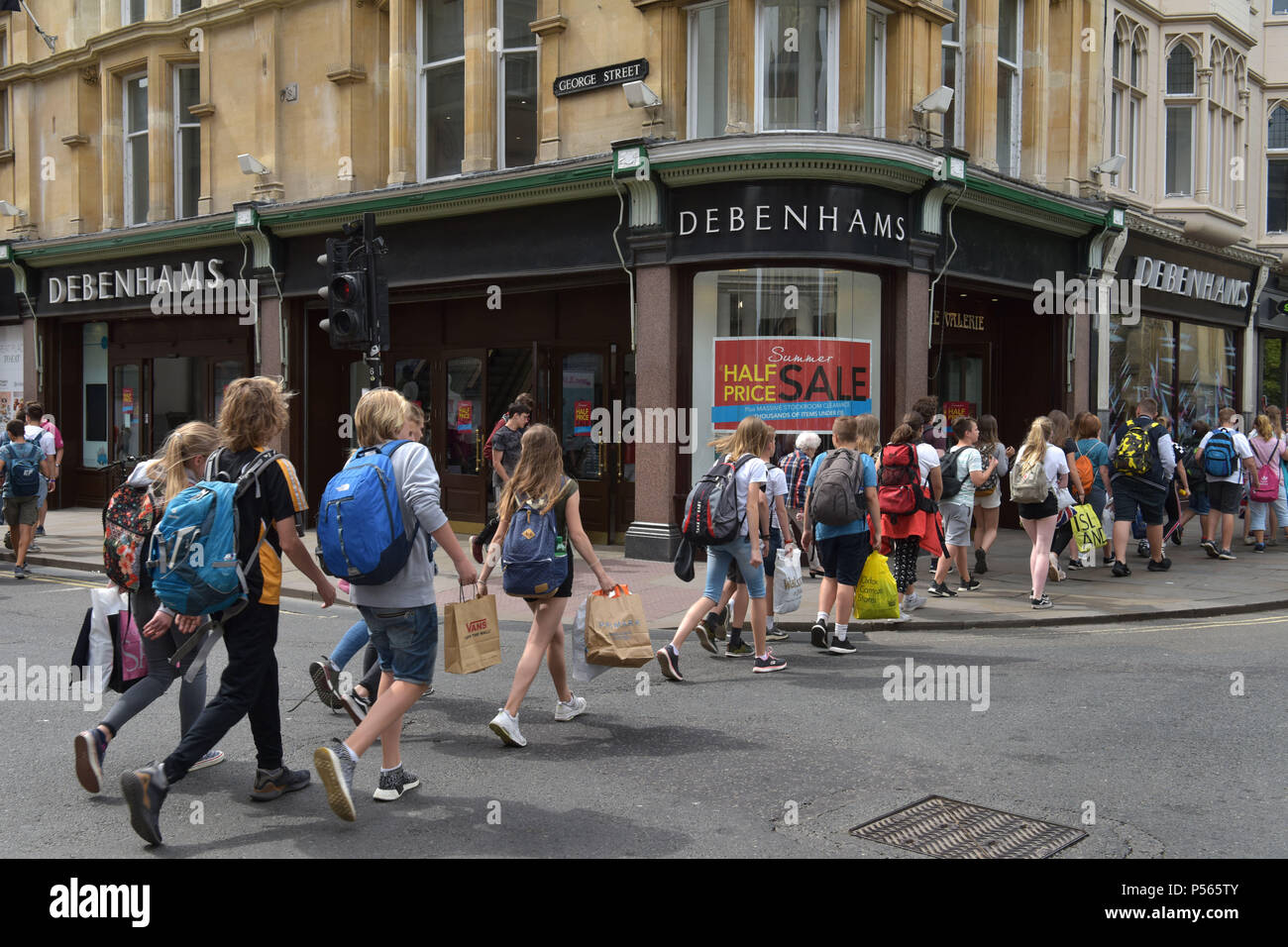 Gli amanti dello shopping, turisti e una linea di studenti a piedi passato i grandi magazzini Debenhams sull'angolo della high street, George Street a Oxford Foto Stock