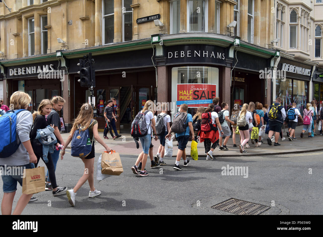 Gli amanti dello shopping, turisti e una linea di studenti a piedi passato i grandi magazzini Debenhams sull'angolo della high street, George Street a Oxford Foto Stock