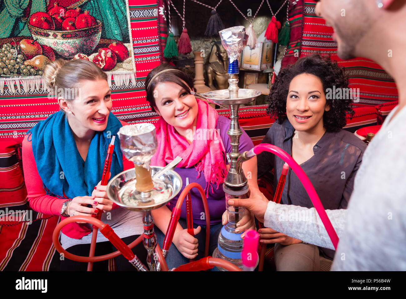 Gruppo su donne e uomini di essere servito un narghilè in shisha cafe Foto Stock