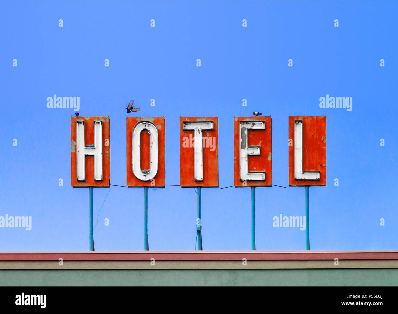 Hotel rosso segno sulla parte superiore di un Dirty old motel isolato sul cielo azzurro sfondo con uccelli Foto Stock