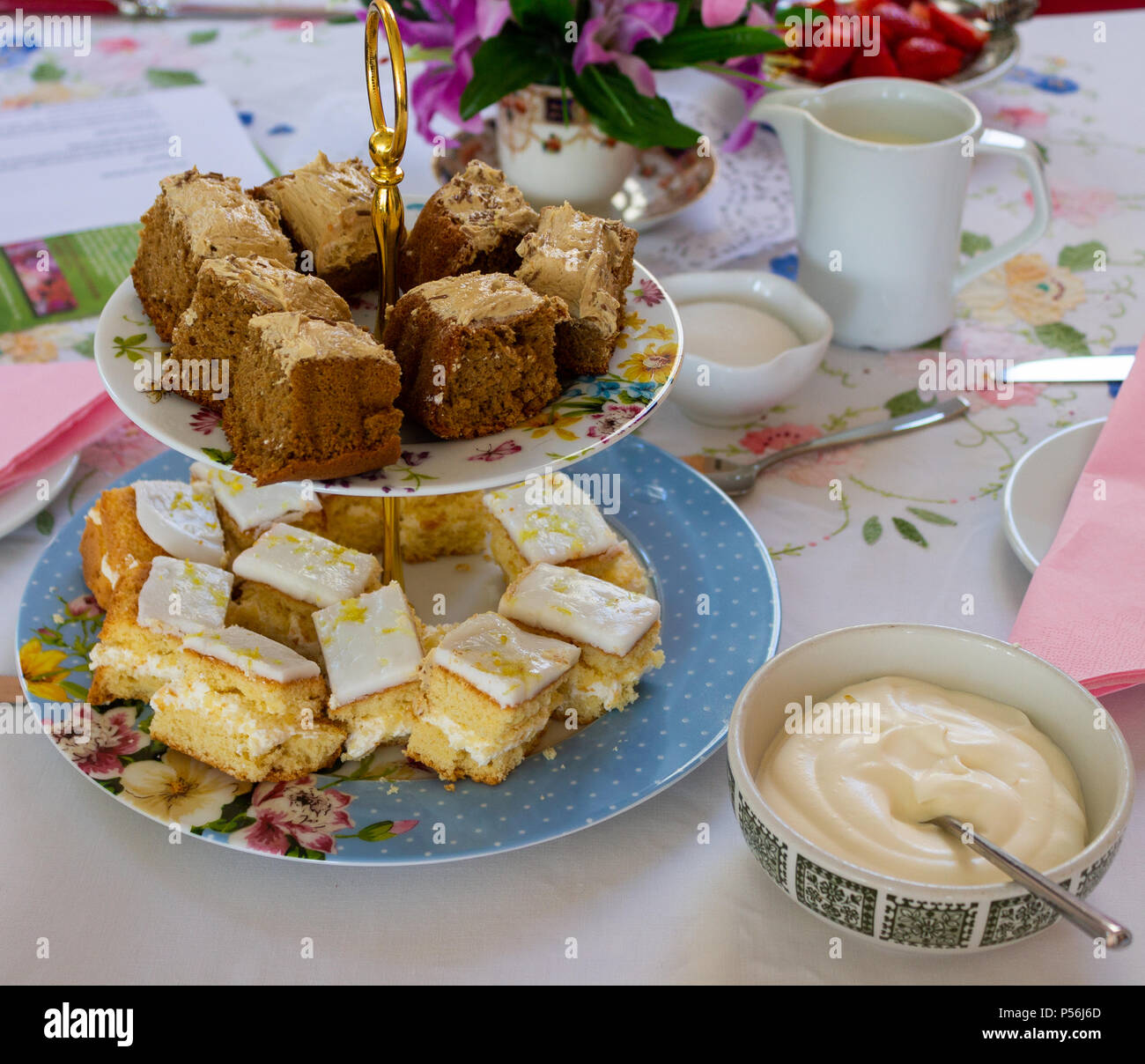 Il tè del pomeriggio con piastre di torte, crema, fragole steso su una tovaglia colorata Foto Stock