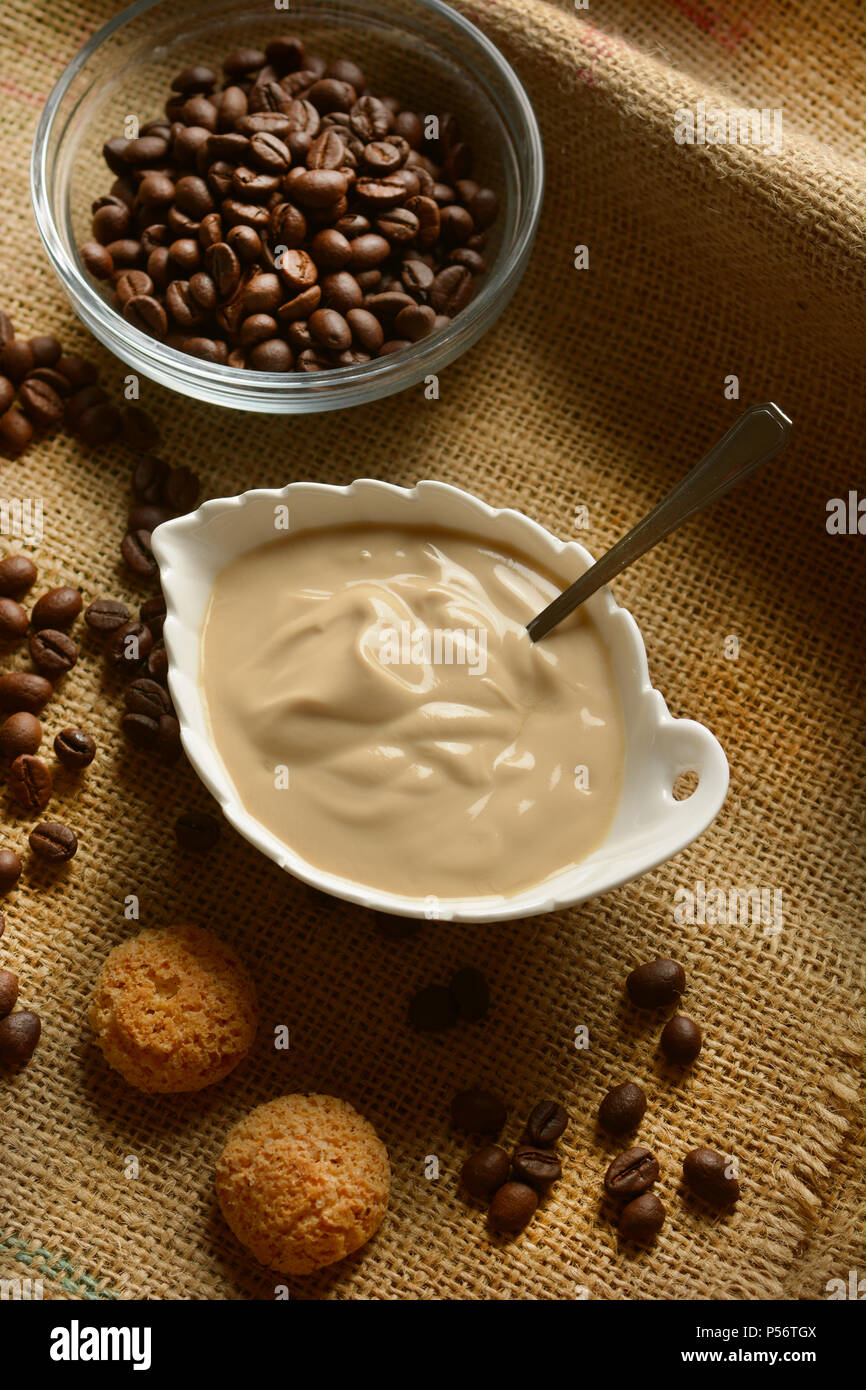 Yogurt caffè nella tazza bianca con chicco di caffè intorno - primo piano Foto Stock