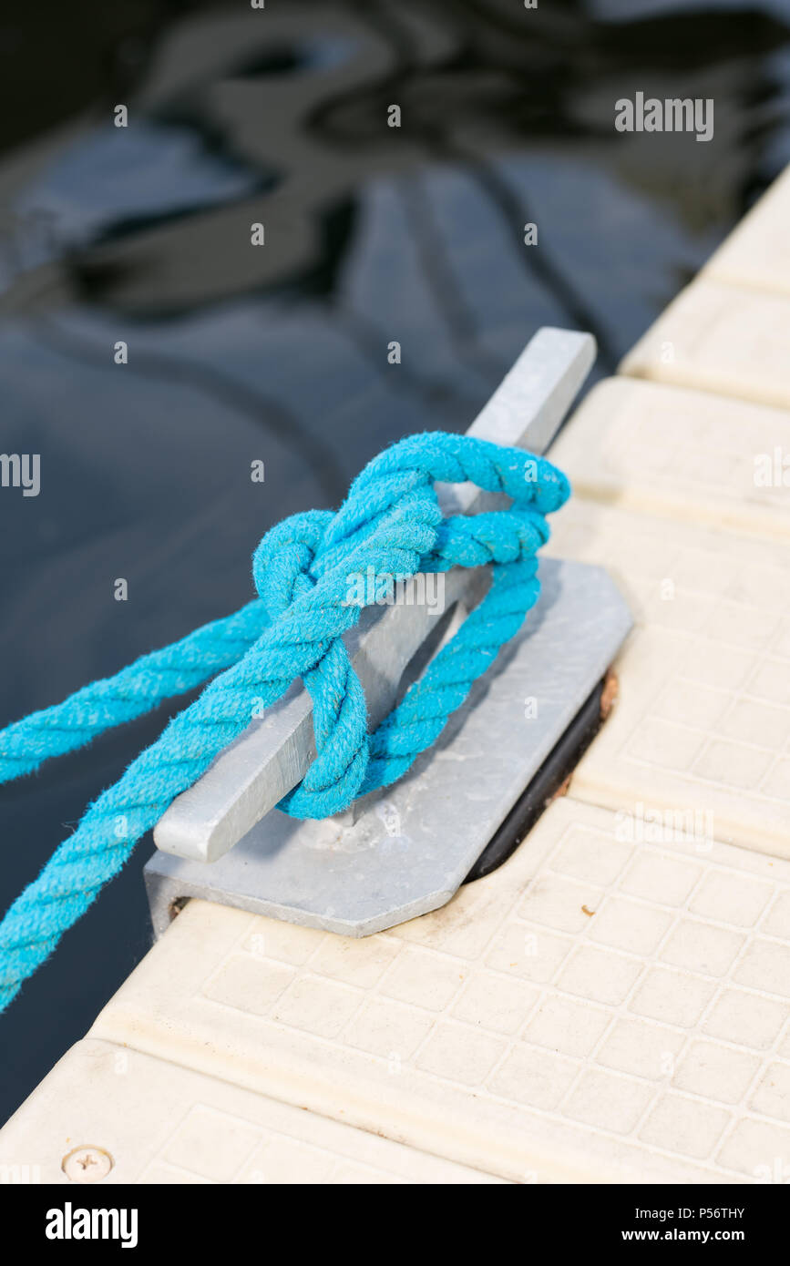 Un gancio su un molo con un annodato Corda blu Foto Stock