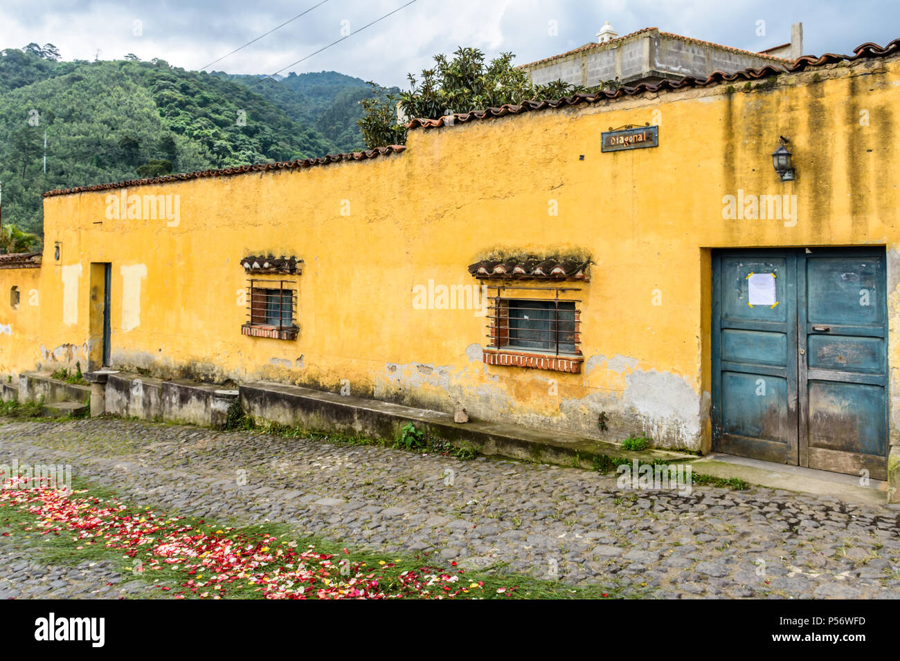 San Juan del Obispo, Guatemala - Giugno 25, 2017: dipinto di giallo house & processione tappeto per Borgo Santo patrono giorno vicino a Colonial Antigua. Foto Stock
