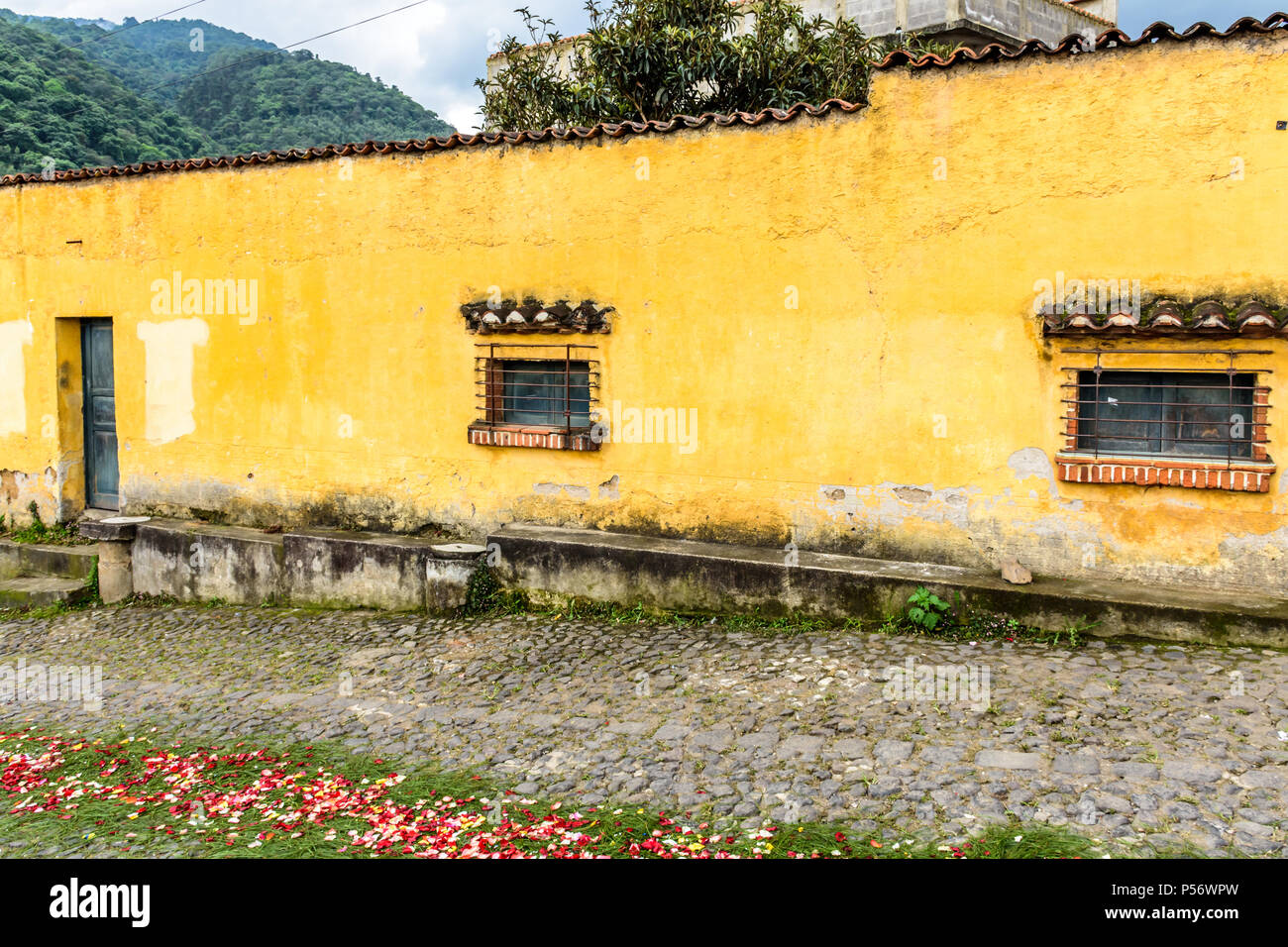 San Juan del Obispo, Guatemala - Giugno 25, 2017: dipinto di giallo house & processione tappeto per Borgo Santo patrono giorno vicino a Colonial Antigua. Foto Stock