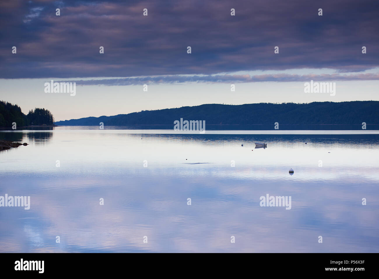 Le nuvole riflettono in acque tranquille del cofano Canal, Washington, al tramonto Foto Stock