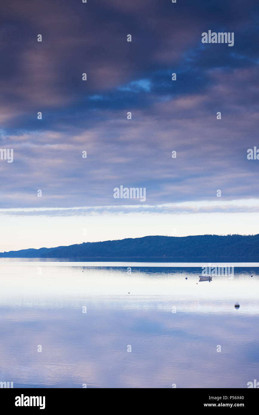 Le nuvole riflettono in acque tranquille del cofano Canal, Washington, al tramonto, orientamento verticale. Foto Stock