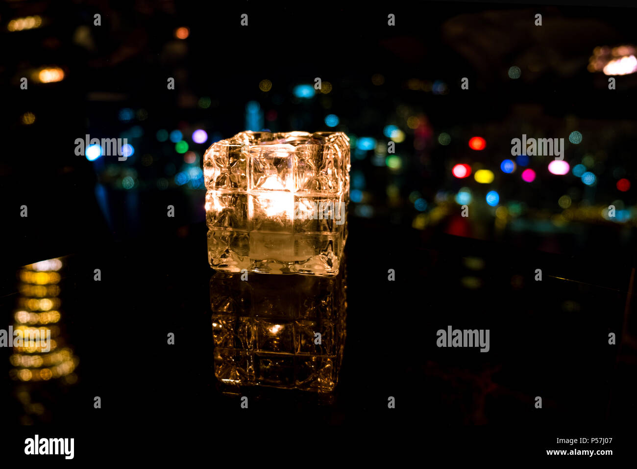 Candela che brucia nel bicchiere di vetro con sfondo astratto Foto Stock