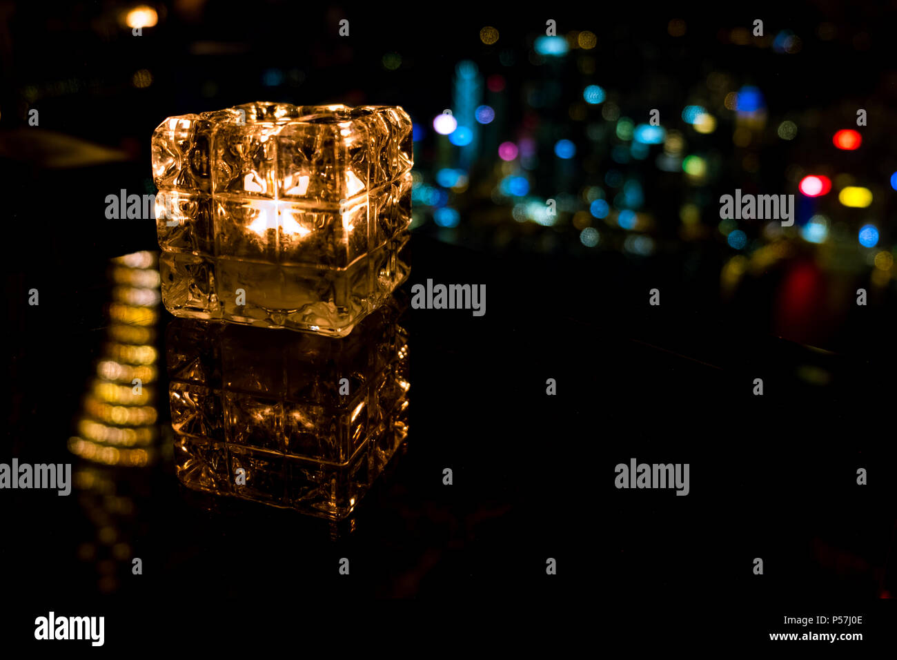 Candela che brucia nel bicchiere di vetro con sfondo astratto Foto Stock