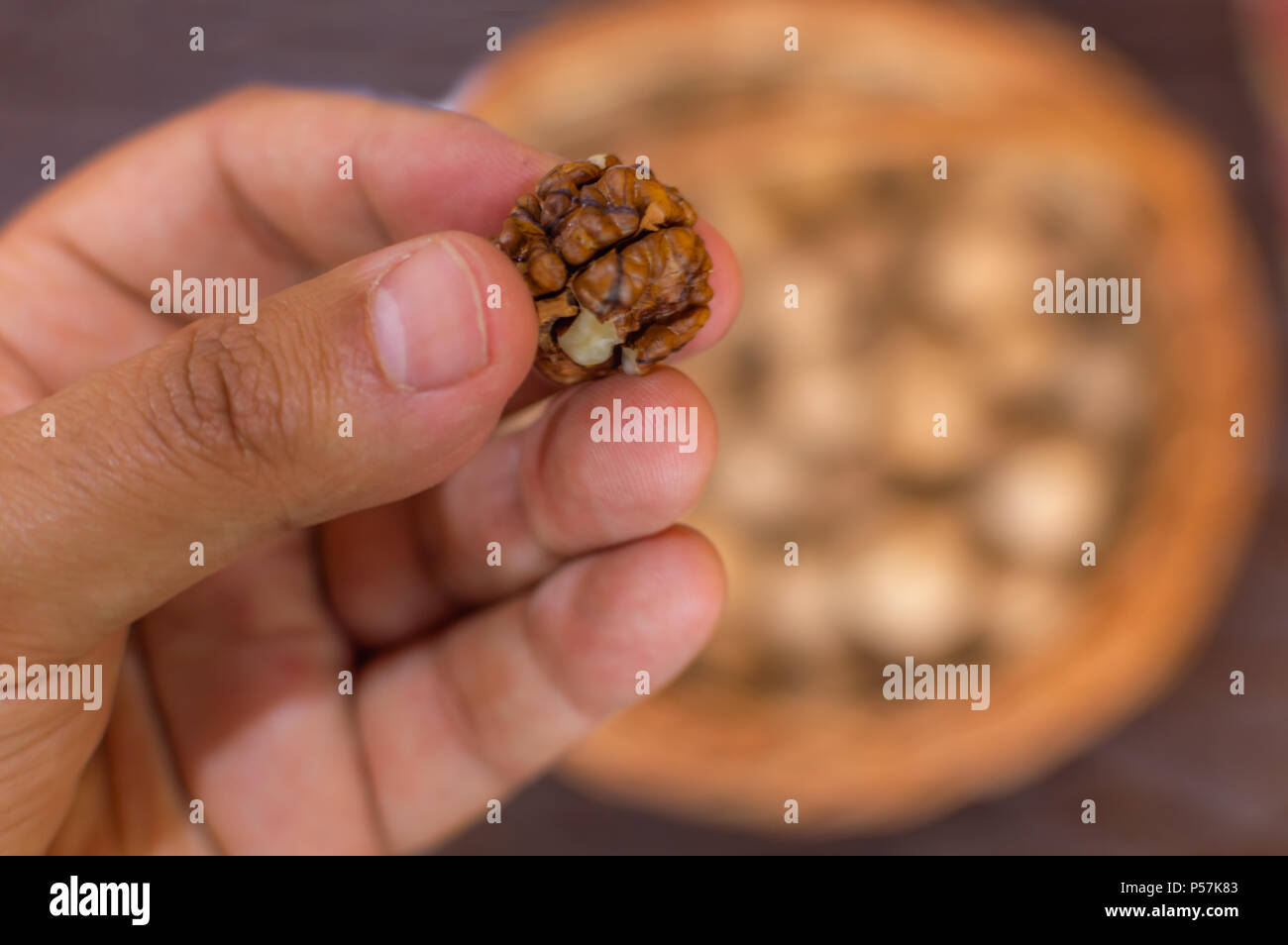 Una persona che mostra e offrendo una noce kernel proveniente da un recipiente grande Foto Stock
