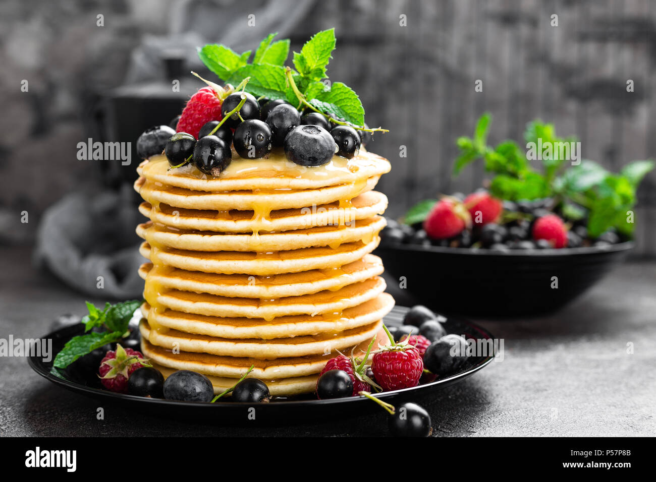 Frittelle con frutti di bosco freschi. Frittelle di lampone, mirtillo, ribes e miele Foto Stock