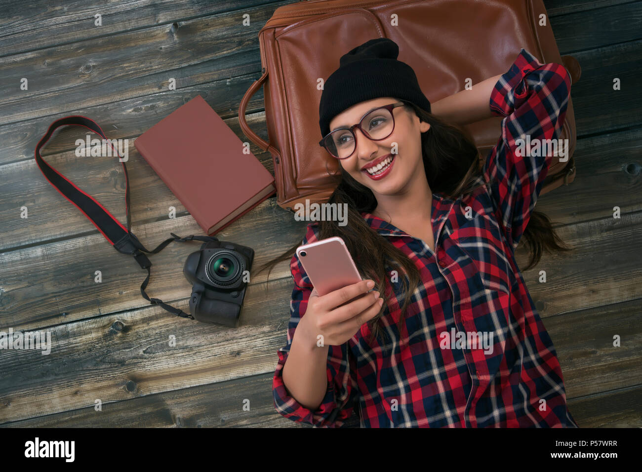 Sorridente turista femminile utilizzando phone giacente su sfondo di legno Foto Stock