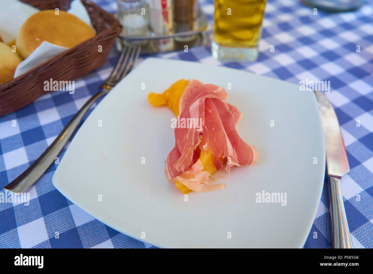 Il Prosciutto di Parma Prosciutto affumicato con melone su una piastra bianca servita su un tradizionalmente condita tavola italiana Foto Stock