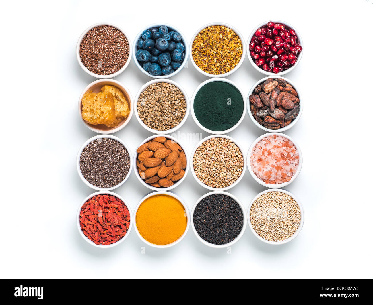 Varie superfoods nel piccolo recipiente isolato su sfondo bianco. Super come chia, spirulina, materie fava di cacao, goji, canapa, quinoa, polline di api, nero sesa Foto Stock