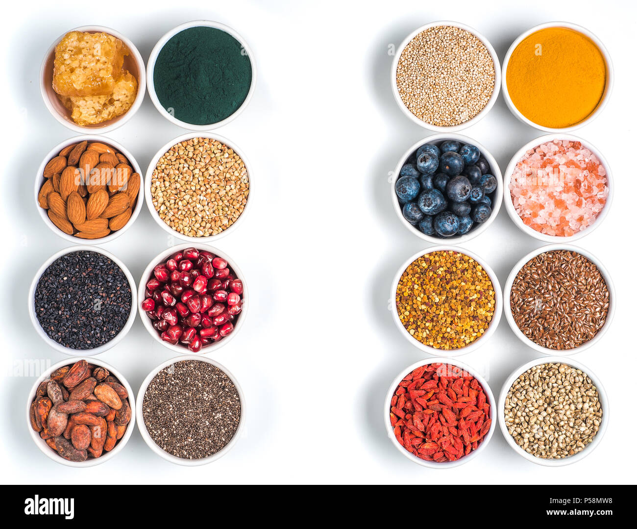 Varie superfoods nel piccolo recipiente isolato su sfondo bianco. Super come chia, spirulina, materie fava di cacao, goji, canapa, quinoa, polline di api, nero sesa Foto Stock