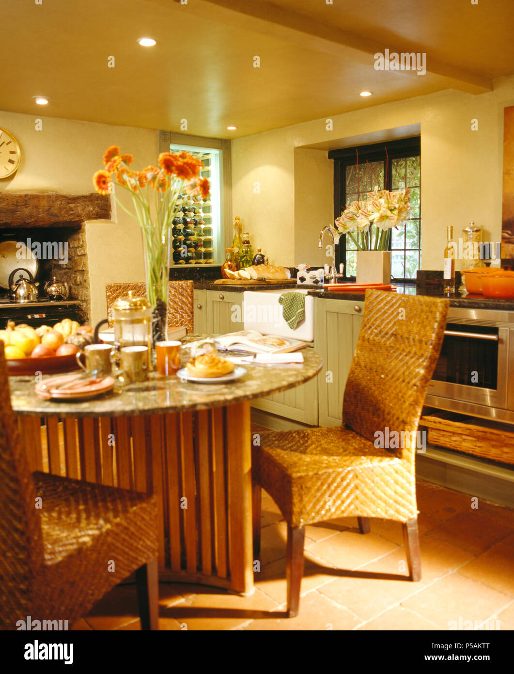 Tall-schienale intrecciato sedie di vimini in granito + legno tabella nella moderna cucina cottage Foto Stock