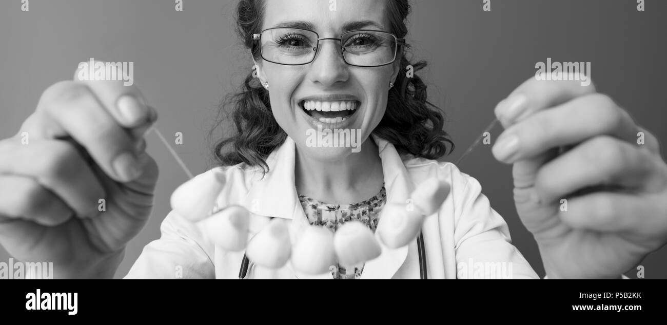 Felice pédiatre medico in bianco manto medici su sfondo mettendo su perle di aglio isolato Foto Stock