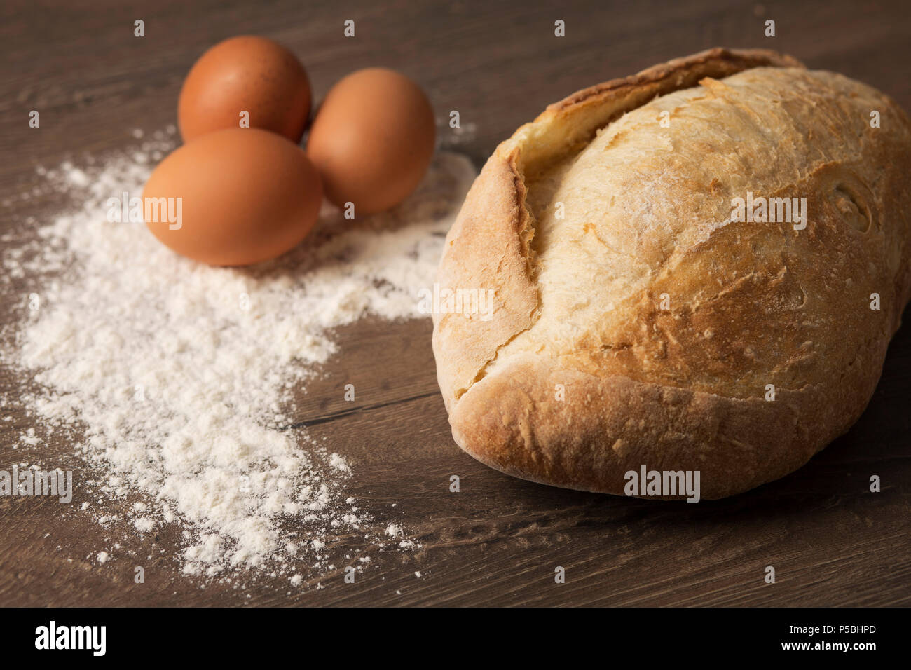 Pane, uova e la farina su un tavolo di legno top Foto Stock