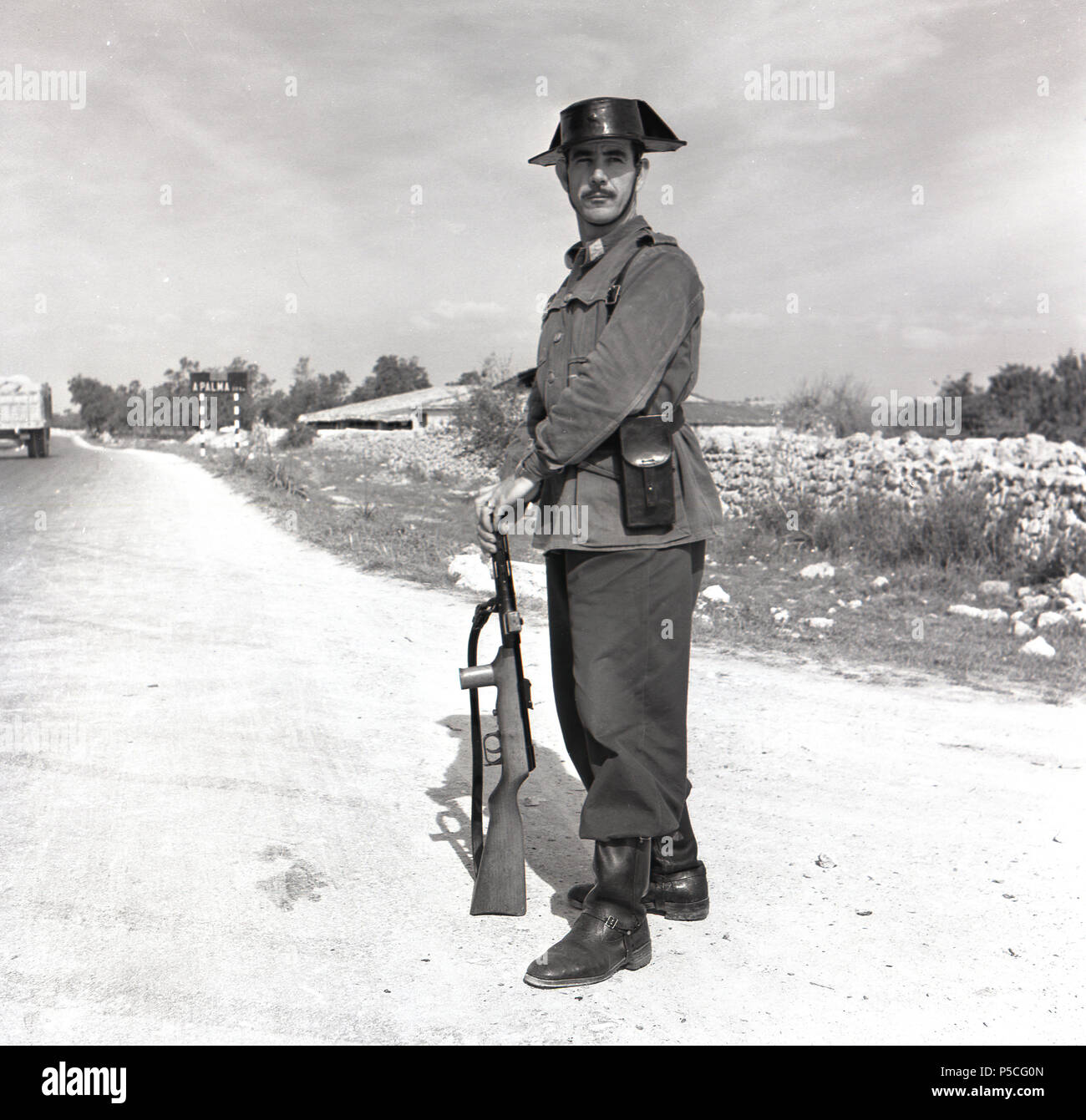 Degli anni Cinquanta, foto di j Allan contanti di una autostrada spagnola poliziotto o di guardia civile in uniforme tradizionale in piedi sul dazio con una strada al di fuori di Palma di Maiorca. Foto Stock