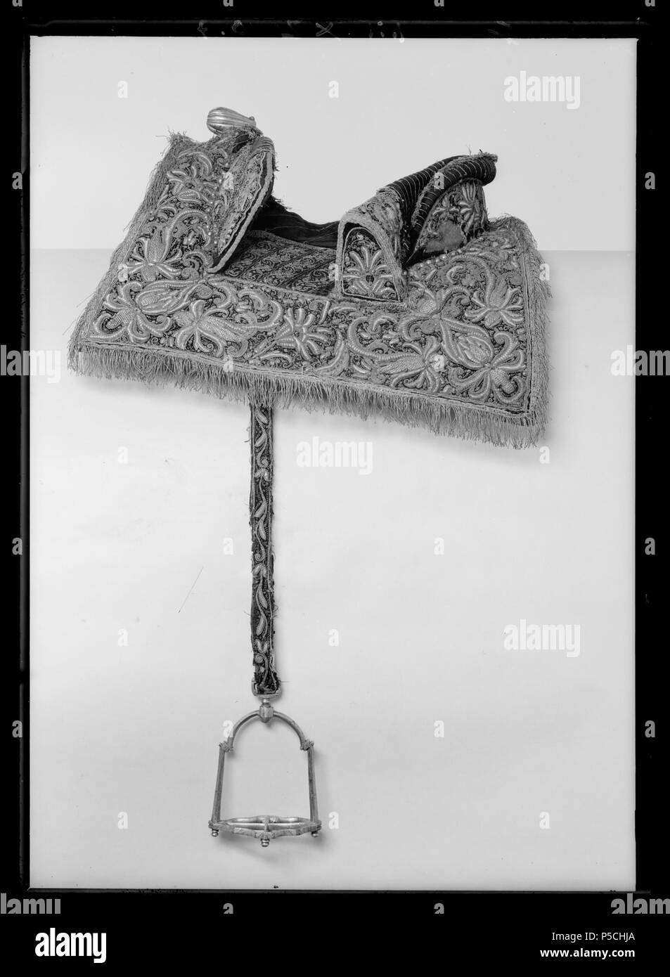 Bomsadel, 1600-talets mitt . Svenska: Bomsadel klädd svart med sammet, rektangulära kappor med yttäckande broderi ho sollievo che ho forma palmetter av, voluter, blad med guld- silvertråd och guld- och silverlan. Kapporna kantade guldfrans med och fodrade med scotto läder. Sitsen med glesa parallella stickningar guldtråd med. Bakbom ca 534 mm allevati, 135 mm hög stödbommar med. Frambom 455 mm allevati 105 hög. Sadelknapp framåt utdragen räfflad av mässing förgylld. Bom klädd väv med. Två söljor för förbygel, två byglar för stigläder, alla av stål. Fyra stroppar läder av för sadelgjord. Framtill hälla klädd me Foto Stock