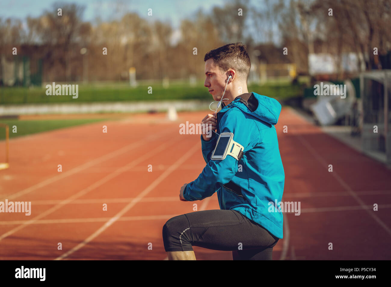 Un maschio di runner con le cuffie sulle orecchie prendendo una pausa in luogo pubblico durante il corso di formazione al di fuori. Copia dello spazio. Foto Stock