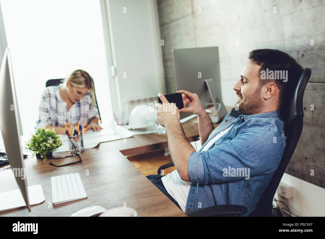 Allegro imprenditore avendo divertimento mentre viene fotografato il suo collega di sesso femminile presso l'ufficio. Foto Stock