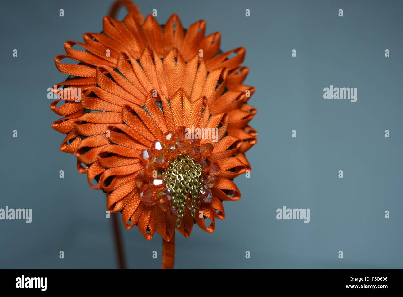Interessante decorazione dei capelli delle donne, look festivo. Splendido cerchio in tessuto realizzato in nastro arancione lucido con decorazioni eleganti posizionate sul bianco. Foto Stock