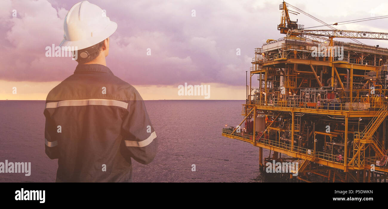 Doppia esposizione di ingegnere tecnico o uomo con casco di sicurezza azionato piattaforma o impianto mediante l'utilizzo di tablet con gas e petrolio al largo backgro piattaforma Foto Stock