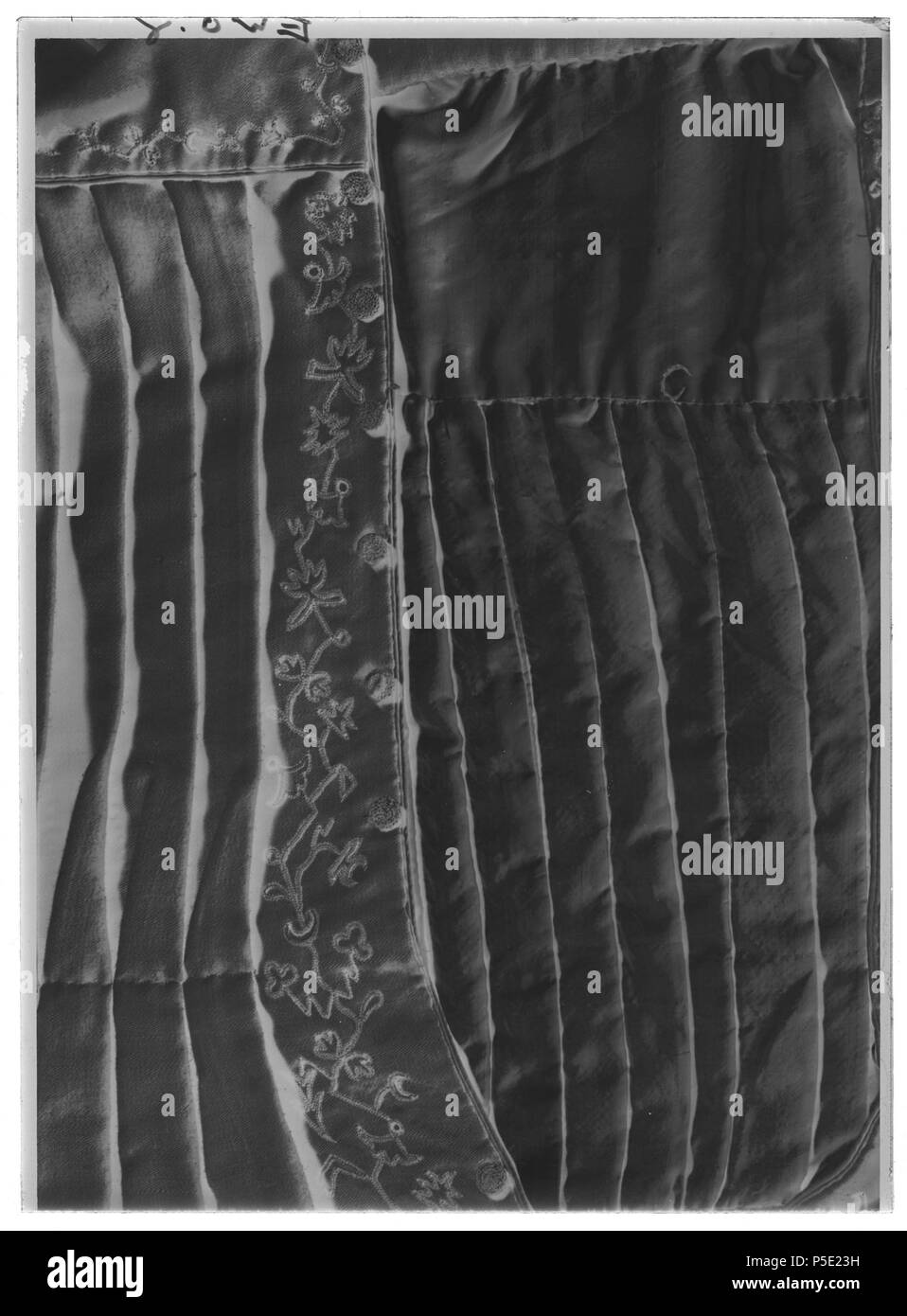 Barnkolt . Svenska: ho ljust gulbrun yllekypert med långa pösärmar och allevati krage, dekorerad med broderier ho tambursöm. Har tilhört Karl XV som barn. Se tillhörande skärp nr Jämför broderns kolt i utförande samma, nr 31413 Koltens tyg har skarvats innan det skurits fino, skarvsömmen ses på dräktens bakre högra sida. Dräkten har formati sammansydda av veck ho liv och ärmar, ingen figurskärning. Ärmen är fästad i en rund öppning ho axlokets yttre kant (1/3-Canc hålets av diam) och ho koltlivet Den har fino a dekorativa knappar framtill hela vägen från hals fino a fåll. På plaggets vänstra slå sitter 1 Foto Stock