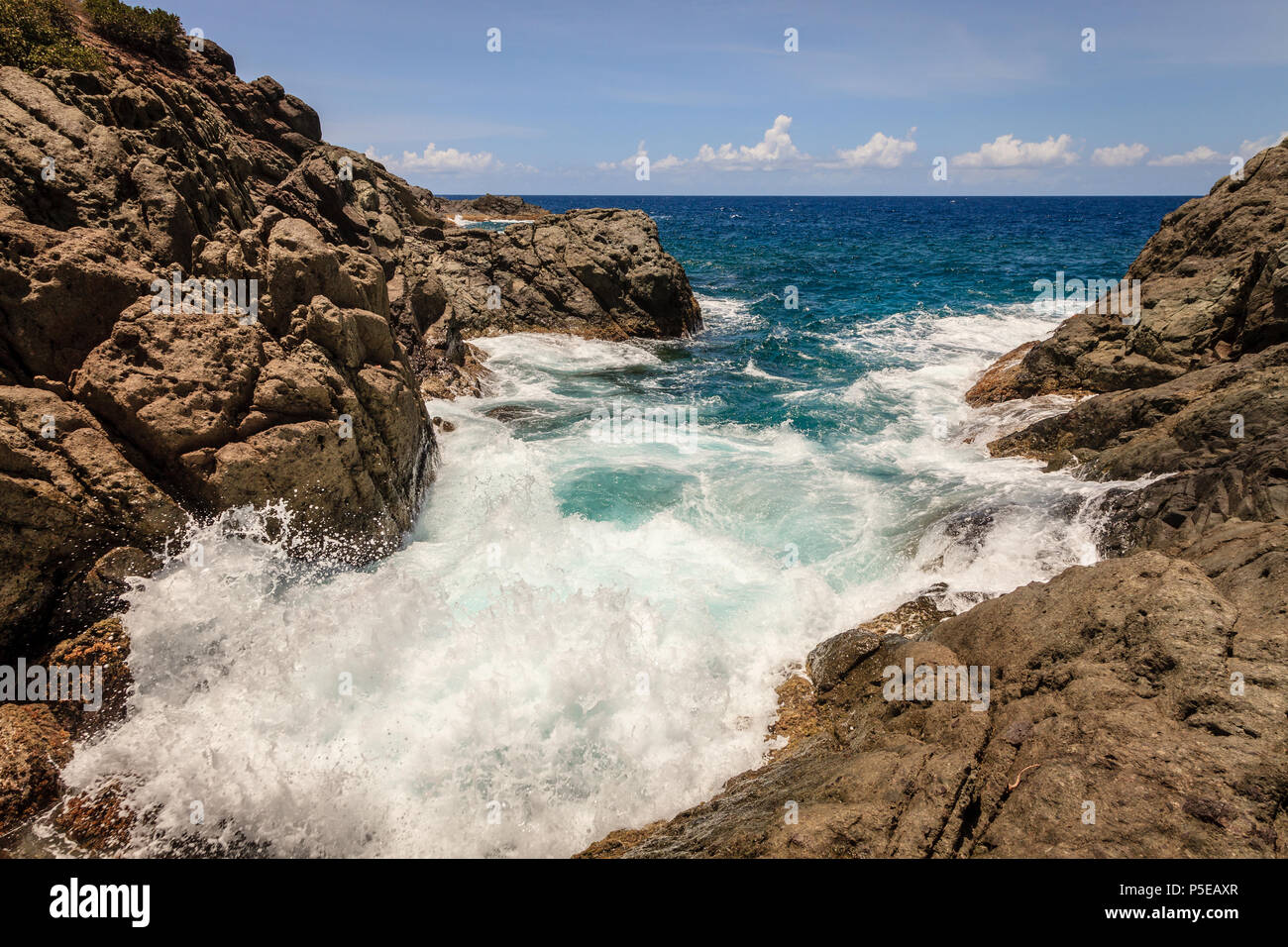 Marea in una piccola caletta rocciosa su un isola in BVI Foto Stock