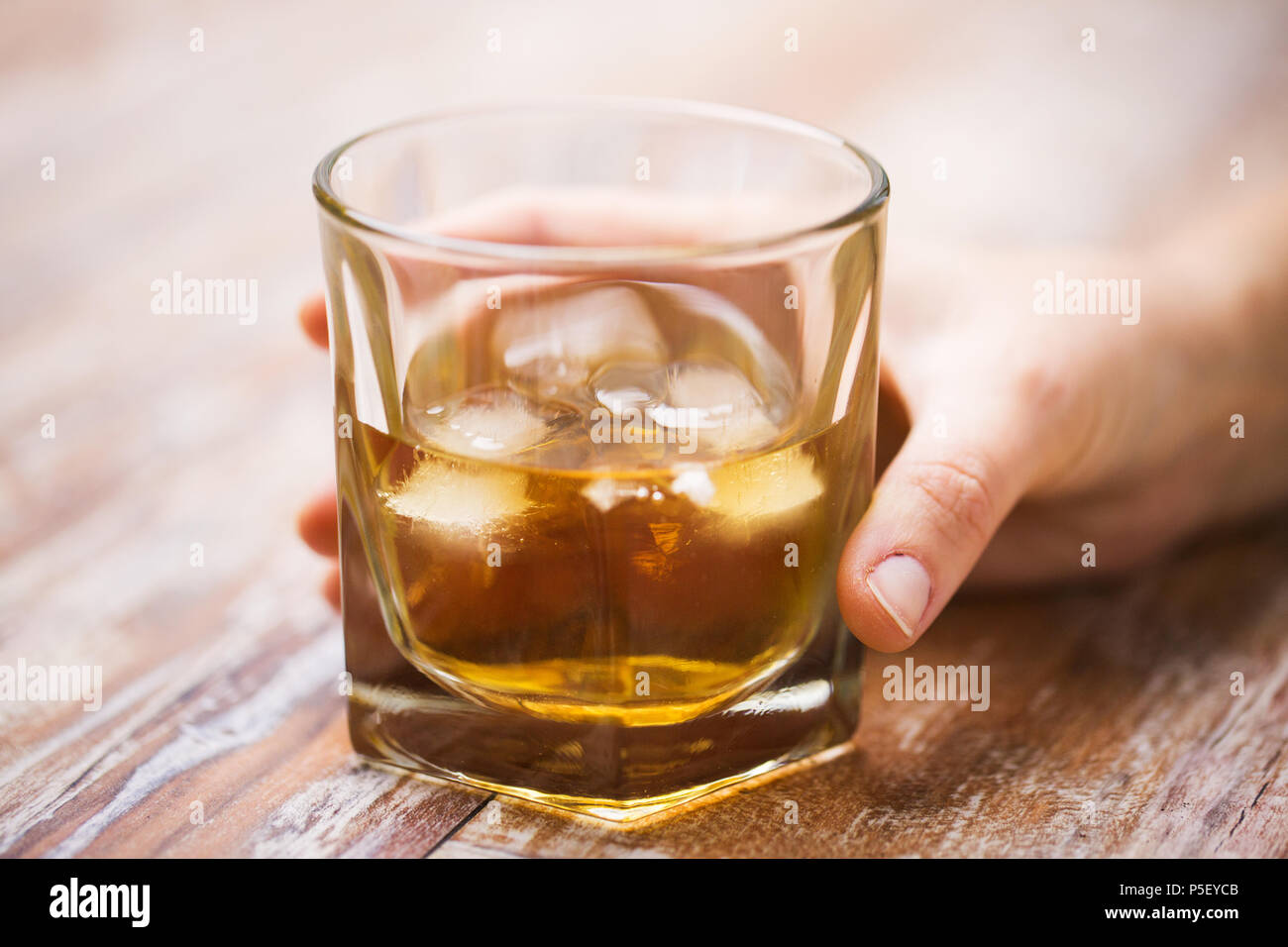 Mano maschio con un bicchiere di alcool sulla tabella Foto stock - Alamy